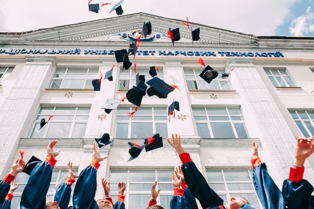 Group of fresh graduates students throwing their academic hat in the air photo.